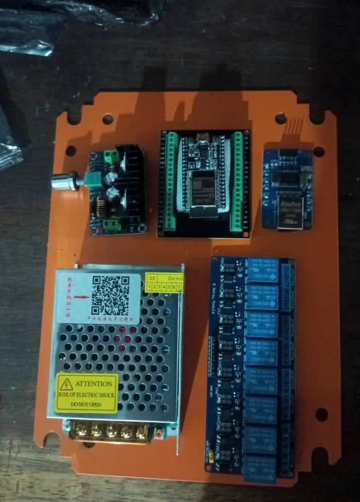 Gabinete de control abierto: fuente de poder, dos placas ESP32 y un bloque de ocho relés montados sobre una placa de soporte.